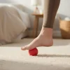 Piros színű labda, jelen esetben a kézerősítő labda alkalmazása a talp masszírozásához